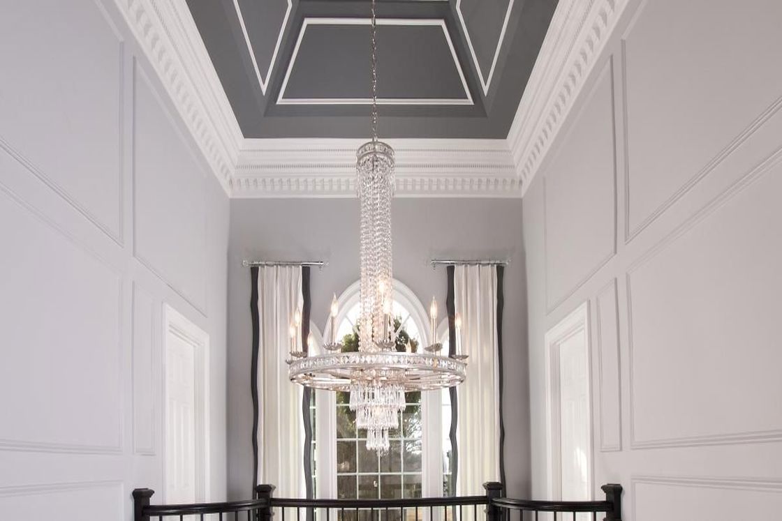 Long glass chandelier hanging from the ceiling of a 2-storey house