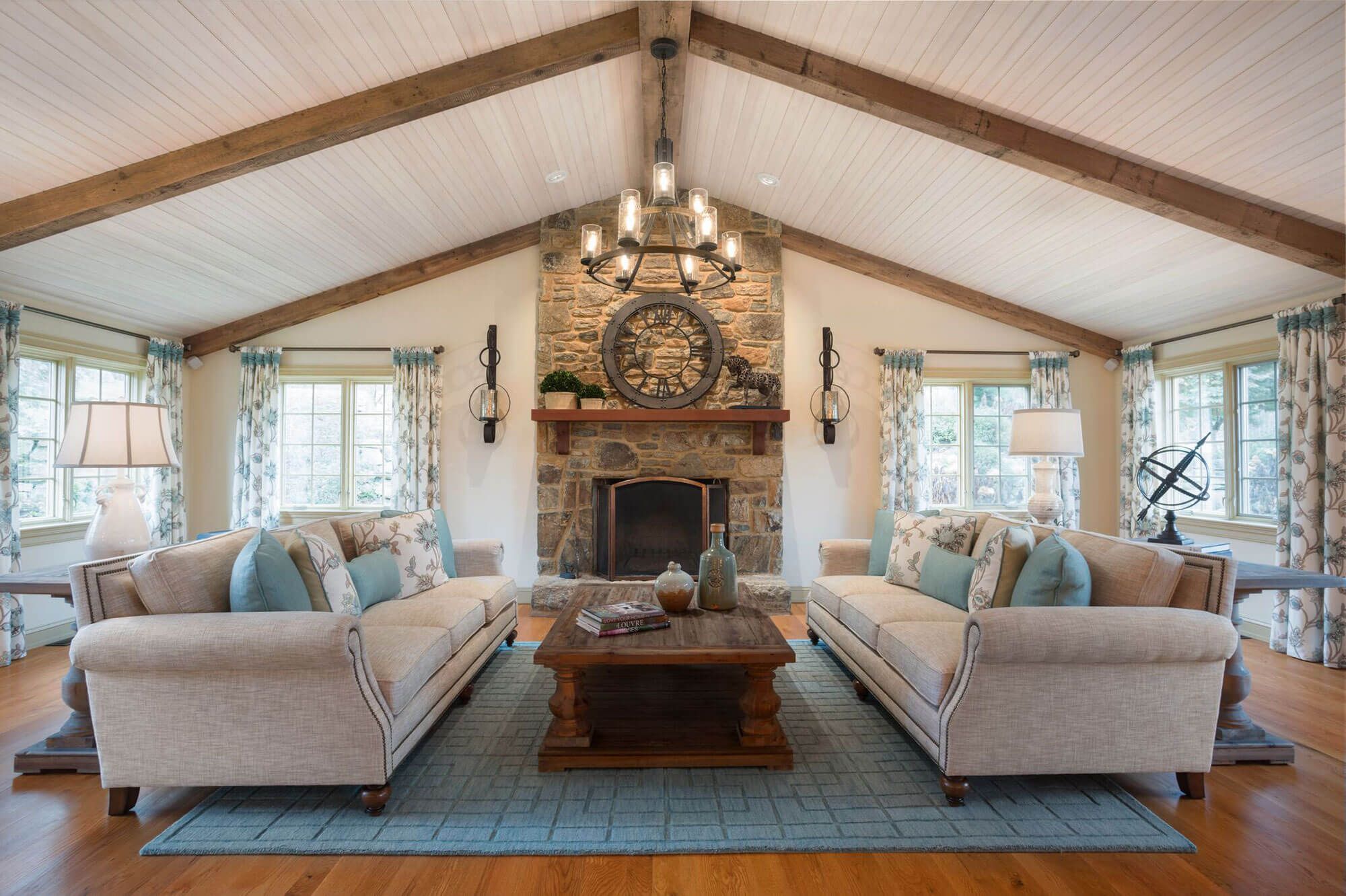 A room with sloped ceiling, fireplace made of textured brick, wooden center table, and couch