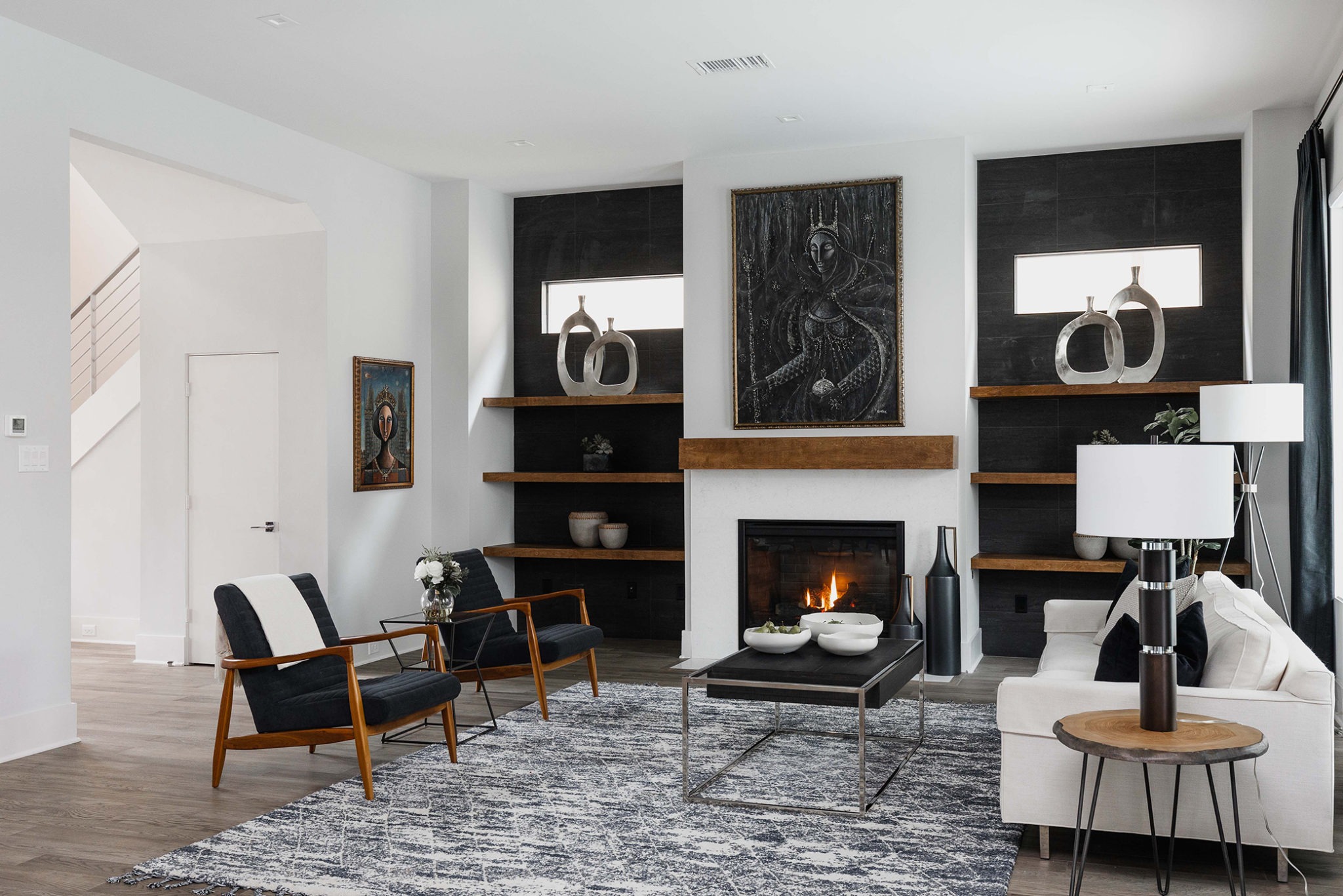 A room with white walls, black chair, center table, and fireplace