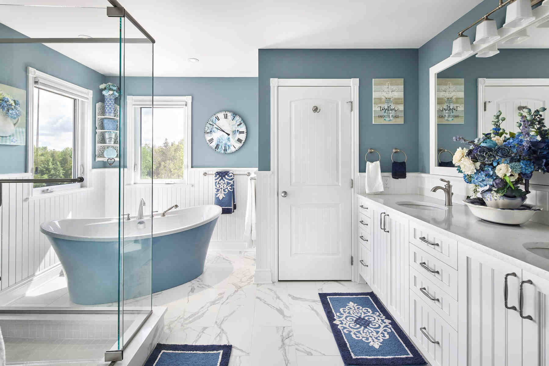 Bathroom with blue and white accents and a bath tub and clear glass shower panels