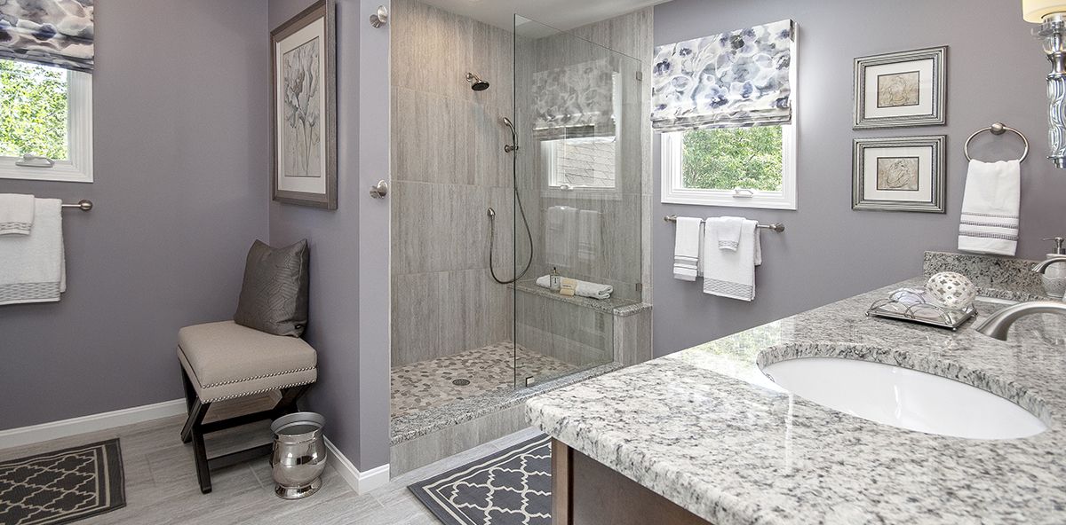 Bathroom with marble countertop, clear glass shower door and resting chair