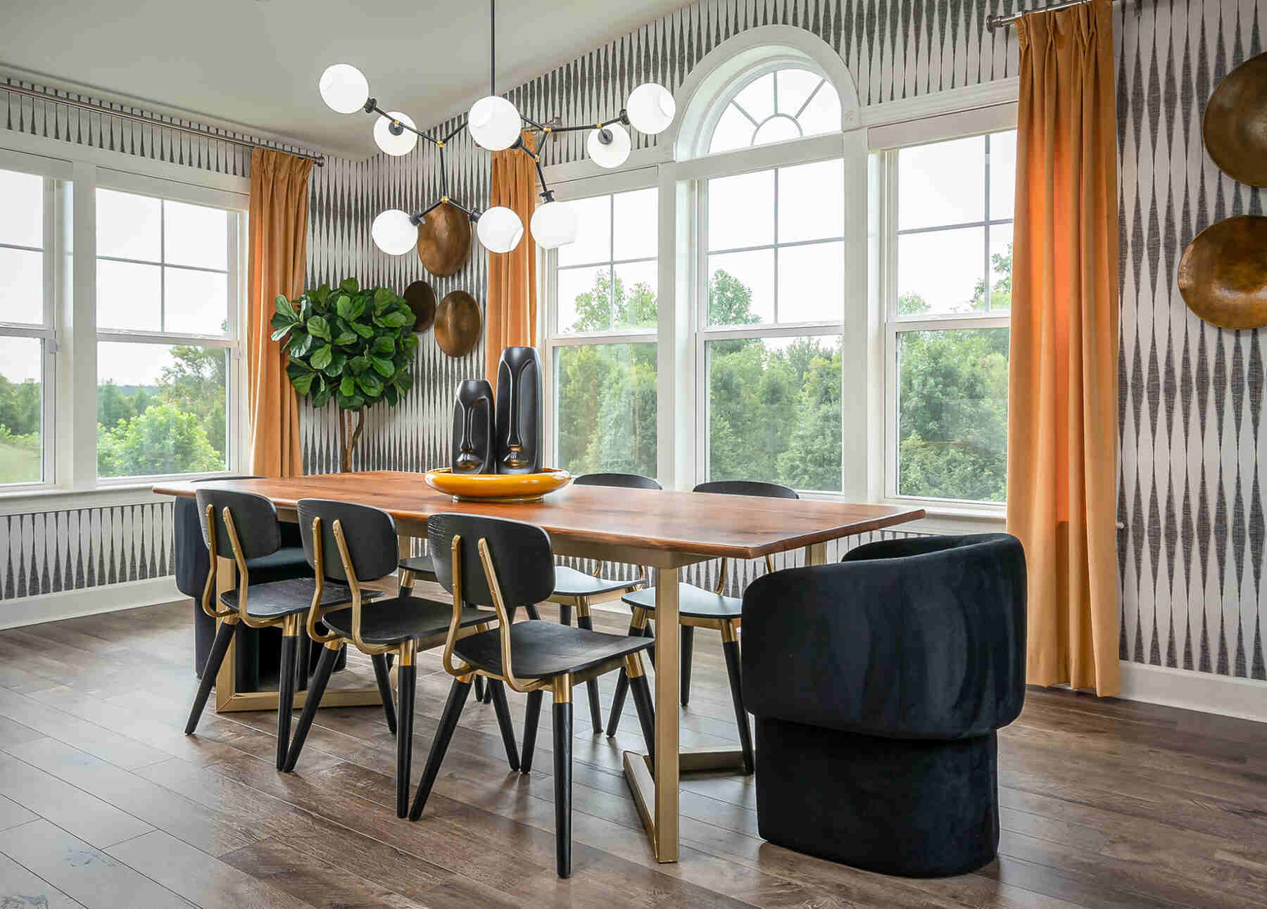 Wooden dining table, with black and gold chairs and low hanging light fixtures