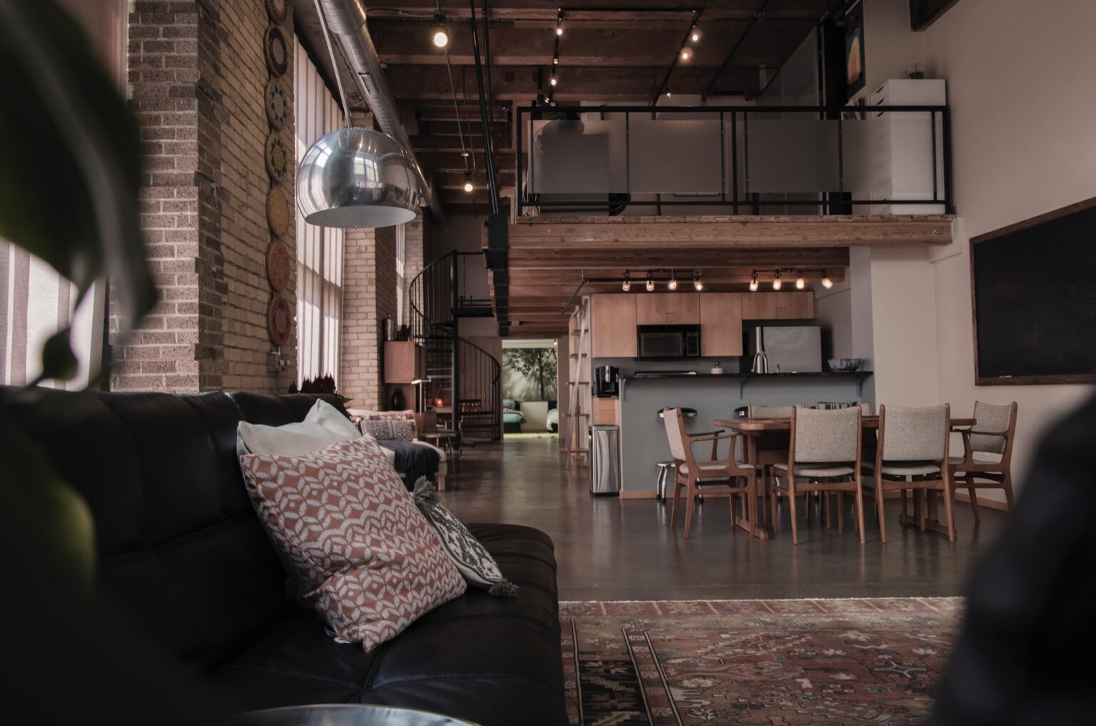 Industrial themed living room with bare floors and walls and a leather couch
