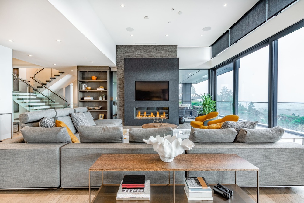 A large living room with a fireplace and grey sectional sofa