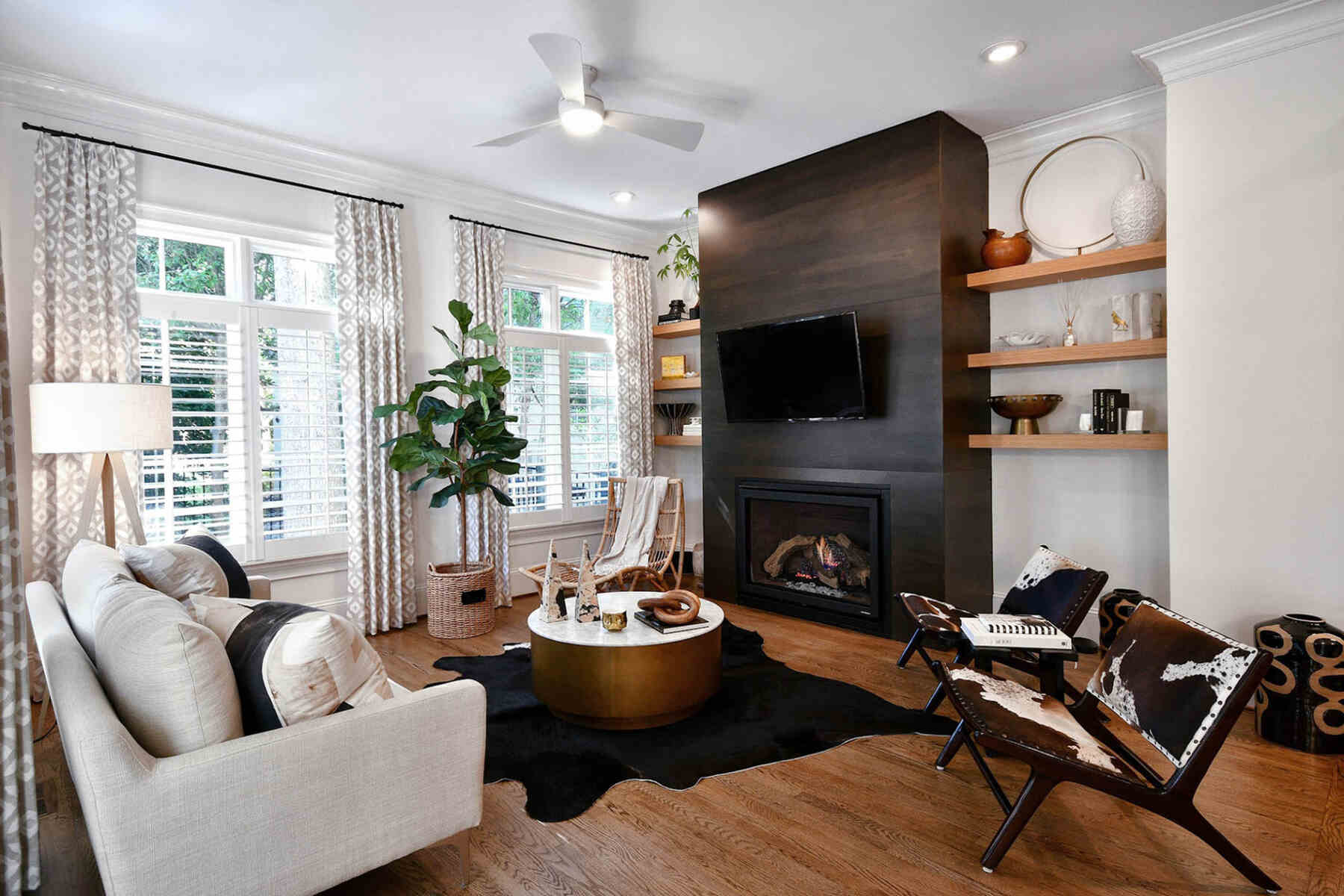 A living room with black fireplace, center table, sofa, chairs, and indoor plant
